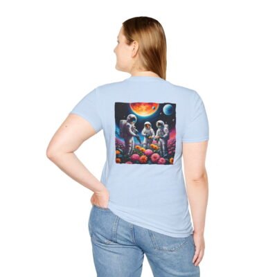 A light blue T-shirt featuring a vibrant graphic of three astronauts in spacesuits watering colorful flowers under a celestial sky planets.