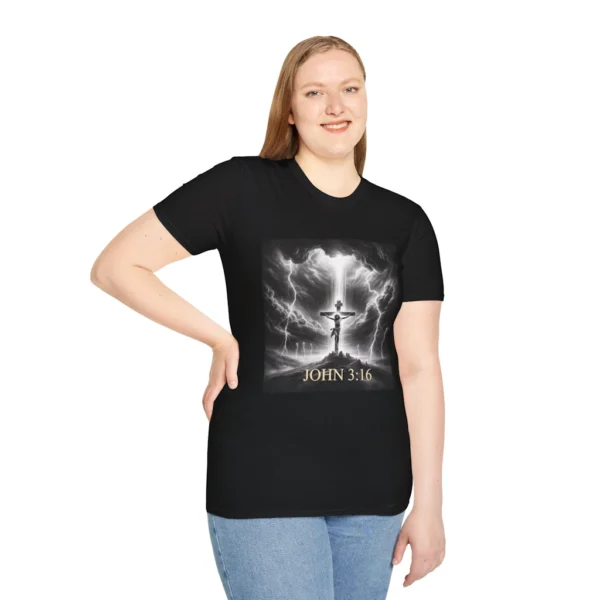 Black Colored "Cross John 3:16" Faith Collection T-shirt on a female model. Has a picture of Jesus on the Cross with a storm and a lot of lightening. in the background.