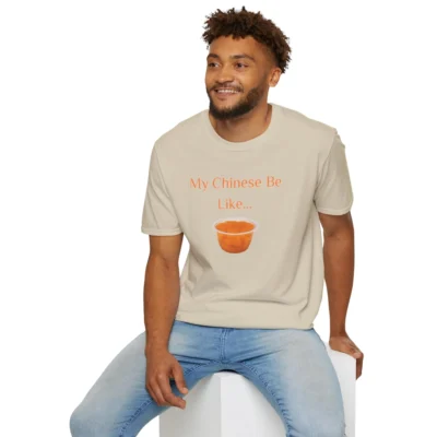 A model wearing a sand colored T-shirt with the words "My Chinese Be Like..." and an image of Mandarin Oranges.