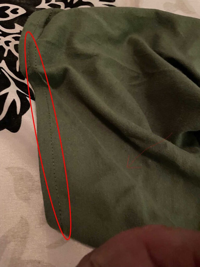 Another angle of threads that have come off of a military green shirt. Highlights in red have been used to show the issue more clearly.