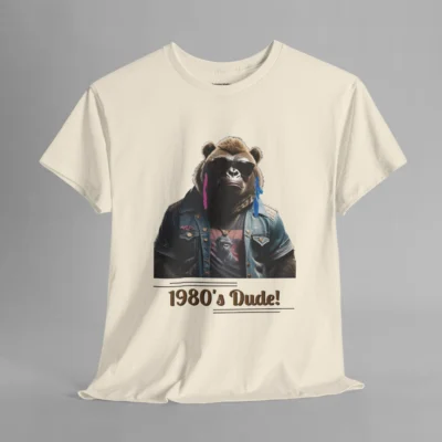 A natural colored t-shirt mockup with one of our iconic gorilla-bear mascots, with pink and purple feather earrings, a swag jean jacket, dark shades, and a graphic tee underneath the jacket. The writing on the shirt says "1980's Dude!", bracketed inside of some horizontal lines.