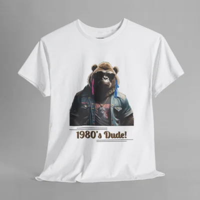 A white colored t-shirt mockup with one of our iconic gorilla-bear mascots, with pink and purple feather earrings, a swag jean jacket, dark shades, and a graphic tee underneath the jacket. The writing on the shirt says "1980's Dude!", bracketed inside of some horizontal lines.