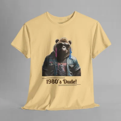 A yellow haze colored t-shirt mockup with one of our iconic gorilla-bear mascots, with pink and purple feather earrings, a swag jean jacket, dark shades, and a graphic tee underneath the jacket. The writing on the shirt says "1980's Dude!", bracketed inside of some horizontal lines.