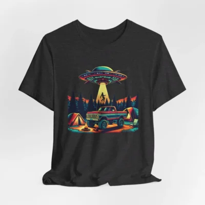Athletic heather colored t-shirt mockup of a camping scene, with a 1980 style pick-up truck, tents, and an alien space ship in the background, abducting a Big Foot looking creature from out of a pine forest. Colors are red, orange, blue, and yellow.