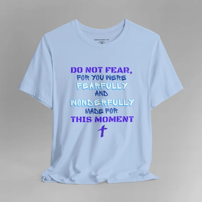 A baby blue colored tee with the words "Do Not Fear, For You Were Fearfully and Wonderfully Made For This Moment" in varying fonts and colors (purple, deep blue, and light aqua blue). There is a graphic, artistic purple cross beneath the words.