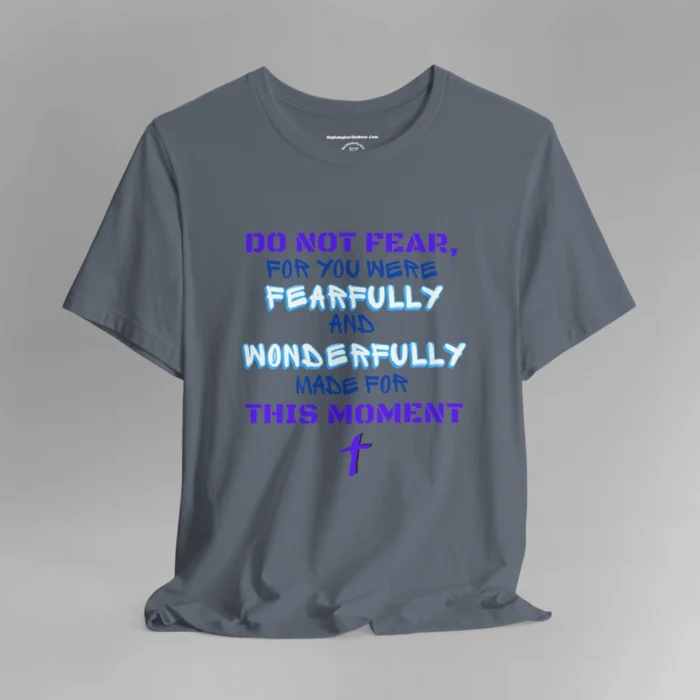 A steel blue colored tee with the words "Do Not Fear, For You Were Fearfully and Wonderfully Made For This Moment" in varying fonts and colors (purple, deep blue, and light aqua blue). There is a graphic, artistic purple cross beneath the words.