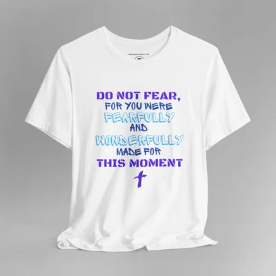 A white colored tee with the words "Do Not Fear, For You Were Fearfully and Wonderfully Made For This Moment" in varying fonts and colors (purple, deep blue, and light aqua blue). There is a graphic, artistic purple cross beneath the words.