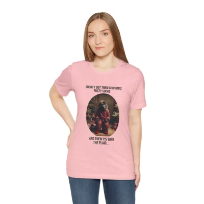 Attractive female showcasing the "Shorty PJs With the Plaid" BigBabyGorillaBear.Com Pink colored graphic tee! This tee has a Big Baby Gorilla Bear with plaid PJs and fuzzy socks in a Christmas scene, with the words "Shorty Got Them Christmas Fuzzy Socks and Them PJs with the Plaid..."