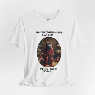 Vertical Layout of a tee showcasing the "Shorty PJs With the Plaid" BigBabyGorillaBear.Com Ash colored graphic tee! This tee has a Big Baby Gorilla Bear with plaid PJs and fuzzy socks in a Christmas scene, with the words "Shorty Got Them Christmas Fuzzy Socks and Them PJs with the Plaid..."