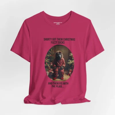 Vertical Layout of a tee showcasing the "Shorty PJs With the Plaid" BigBabyGorillaBear.Com Berry colored graphic tee! This tee has a Big Baby Gorilla Bear with plaid PJs and fuzzy socks in a Christmas scene, with the words "Shorty Got Them Christmas Fuzzy Socks and Them PJs with the Plaid..."