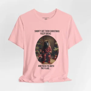 Vertical Layout of a tee showcasing the "Shorty PJs With the Plaid" BigBabyGorillaBear.Com Pink colored graphic tee! This tee has a Big Baby Gorilla Bear with plaid PJs and fuzzy socks in a Christmas scene, with the words "Shorty Got Them Christmas Fuzzy Socks and Them PJs with the Plaid..."