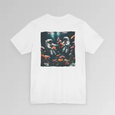 An ash shirt with a surreal image on the backside of a tee of two astronauts in space suits swimming in the ocean, with colorful coral, purple, white, peach, and yellow flowers. One astronaut is holding a flower.