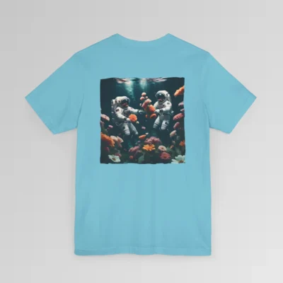 A turquoise shirt with a surreal image on the backside of a tee of two astronauts in space suits swimming in the ocean, with colorful coral, purple, white, peach, and yellow flowers. One astronaut is holding a flower.