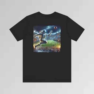 A black colored graphic tee with an image of an astronaut leaping high above crowds in a football stadium at night, about to catch a football, on the back of the tee. The background is warped, as if the astronaut is moving at super-human speeds.