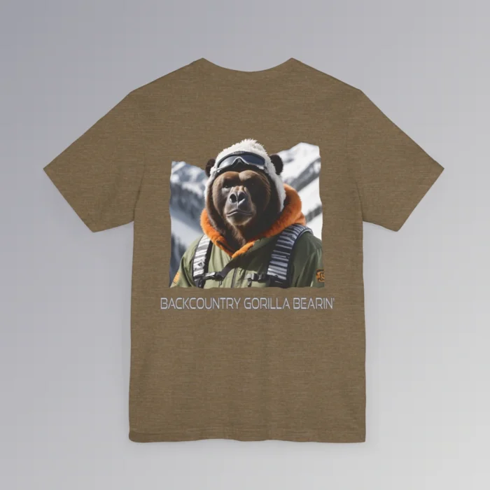 An olive heather colored tee with a backside graphic of one of our iconic gorilla grizzly bears, fully dressed in an army/olive colored snow jacket with orange trim, white toboggan, and a backpack. There are snowy mountains in the background. Beneath the image is text that reads "Backcountry Gorilla Bearin'".