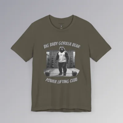 An army colored tee with an image of one of our iconic gorilla-bear hybrid creatures in a tank top, in a gym, with the image in grayscale color scheme. 3D print is above and below the image. On top, it says "Big Baby Gorilla Bear", and on bottom it says "Power Lifting Club". Graphic on front.