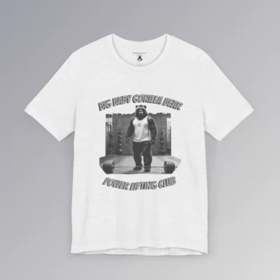 An ash colored tee with an image of one of our iconic gorilla-bear hybrid creatures in a tank top, in a gym, with the image in grayscale color scheme. 3D print is above and below the image. On top, it says "Big Baby Gorilla Bear", and on bottom it says "Power Lifting Club". Graphic on front.