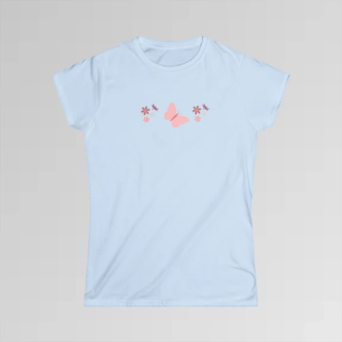 A light blue colored shirt with a pink butterfly with a coral-colored body in the center, and pink, white, and blush colored flowers, and blush colored dragonflies...in a pattern going vertically across the tee.