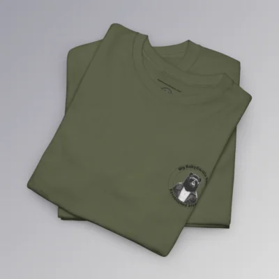 A folded, military green colored t-shirt with the Big Baby Gorilla Bear Logo on the front. The logo is circular, with a circle inside a circle, Inside the circles is "Big Baby Gorilla Bear" on the top and :"Established 2024" on the bottom. In the center of the circle, is our mascot, a grizzly-gorilla bear character, with a leather jacket, and shades, and a gold cross chain.