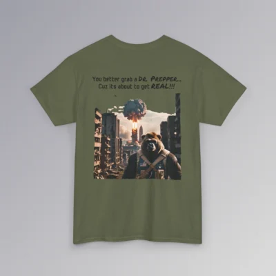 A military green colored shirt with one of our iconic grizzly bear-gorilla character dressed in prepping/military gear. In the background, a mushroom cloud is occurring in a ruined city. The writing above the graphic says "You better grab a Dr. Prepper, Cuz its about to get real!!!".