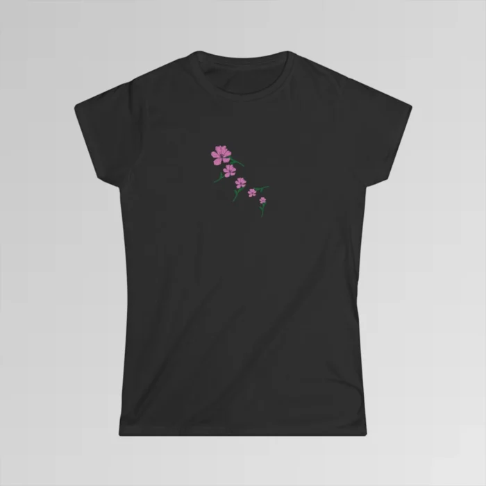 A black colored shirt with blush-colored flowers that appear falling down the shirt, from left to right, in a diagonal pattern, with green stems pointing in different directions as the flowers "fall".