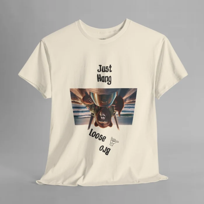 A natural colored graphic tee with one of our iconic bear-gorilla hybrid creatures riding on top of a fighter over a beach. The image is turned upside down, and in the shape of an upside down trapezoid. Above the image is writing that says " Just Hang", and beneath the image it says "Loose Bro" at an angle, and with a hang-loose hand gesture clip art.
