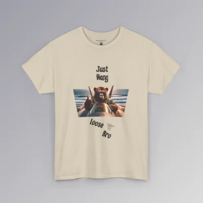 The "Just Hang Loose" BigBabyGorillaBear.Com signature t-shirts. This shirt has one of our iconic gorilla bear creatures riding on top of a fighter jet, throwing a hang loose hand gesture. The background is a beach and ocean the jet is flying over. Above the image it says "Just Hang" and beneath the image, the font is angled down about 30 degrees, and says "Loose Bro" with a clipart of a hand gesture next to loose". Tee color is sand.