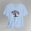 A baby blue t-shirt with a graphic image of a blued liquid metal tree, with leaves of orange, pink, coral, and magenta on the front of the t-shirt.