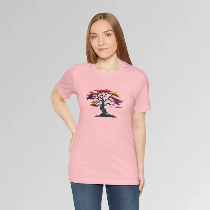 A woman wearing a pink t-shirt with a graphic image of a blued liquid metal tree, with leaves of orange, pink, coral, and magenta on the front of the t-shirt.