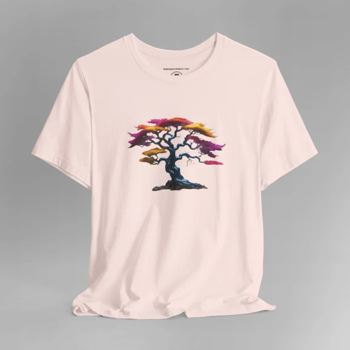 A soft pink t-shirt with a graphic image of a blued liquid metal tree, with leaves of orange, pink, coral, and magenta on the front of the t-shirt.