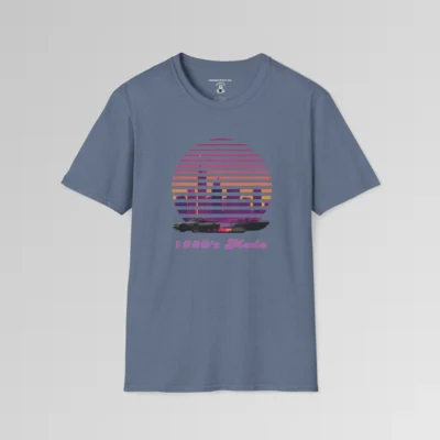 A heather indigo shirt with a view of the Miami, FL skyline (not necessarily an accurate view), with a blind effect, as if it appears as if the viewer is looking through window blinds. At the bottom is a generic 1980's style convertible, and a speed boat. Beneath the image says "1980's Mode" . The image has pinks, oranges, greys, purples, and some yellows.