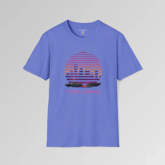 A heather royal shirt with a view of the Miami, FL skyline (not necessarily an accurate view), with a blind effect, as if it appears as if the viewer is looking through window blinds. At the bottom is a generic 1980's style convertible, and a speed boat. Beneath the image says "1980's Mode" . The image has pinks, oranges, greys, purples, and some yellows.