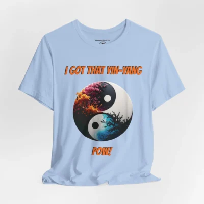 An baby blue t-shirt with a Black and white yin-yang, that appears to have trees growing out of the center. The trees are orang and pink, and blacked out. The bottom part of the yin-yang has blue swirls. "I Got That Yin-Yang" is above the image. "Pow!" is beneath the image. The graphic is on the front of the shirt.