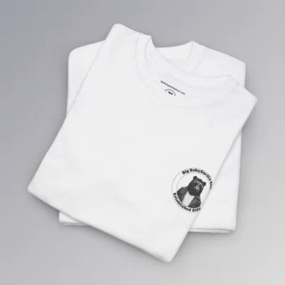 Frontside of a folded white tee, with the circular Big Baby gorilla Bear 2024 logo, with two circles, and on the inside, the image of our iconic mascot in leather jacket and shades. Between the inner circles of the logo, on the top is the brand name, and on the bottom it says "established 2024".