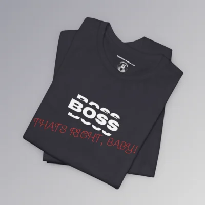 A folded Tee mockup with the word "BOSS" in white, and a rectangle that matches the shirt color around the word. Beneath the word, in slightly smaller white font is a partial view of the word "BOSS", on both bottom and top of the original word, all in a boxy-ish font. Beneath this, in a red handwriting font, is the phrase "Thats Right, Baby!". - Dark grey colored.