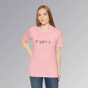 A model wearing the "It Wasn't Me" graphic tee, featuring magazine cutout letters of various fonts and colors arranged to spell out "It Wasn't Me", on the front of the t-shirt.