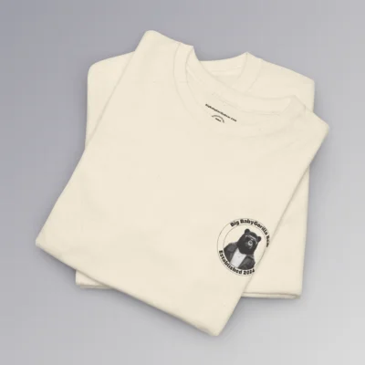 Frontside of a folded natural colored tee, with the circular Big Baby gorilla Bear 2024 logo, with two circles, and on the inside, the image of our iconic mascot in leather jacket and shades. Between the inner circles of the logo, on the top is the brand name, and on the bottom it says "established 2024". The "Kiss The Sun Breakdancing" T-shirt.