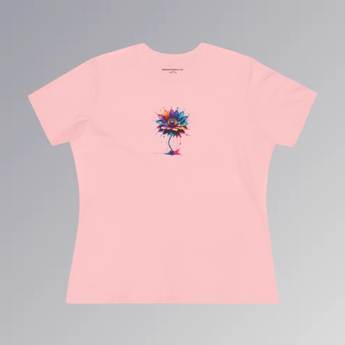 A pink colored t-shirt with a vibrant, multi-colored flower on the front of the t-shirt. The graphic looks as if it has been created with splashing vibrant colored paints, with hues of blue, violet, pink, and orange.