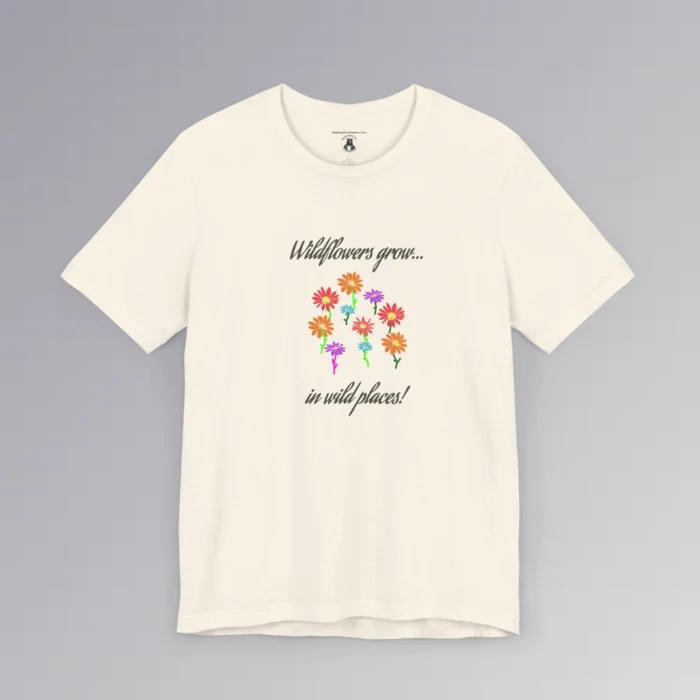 Natural colored t-shirt with blue, red, orange, and purple coneflower-like flowers, with green and mauve colored stems. In a handwriting font, is says "Wildflowers grow..." above the flowers, and "in wild places!" beneath the flowers.