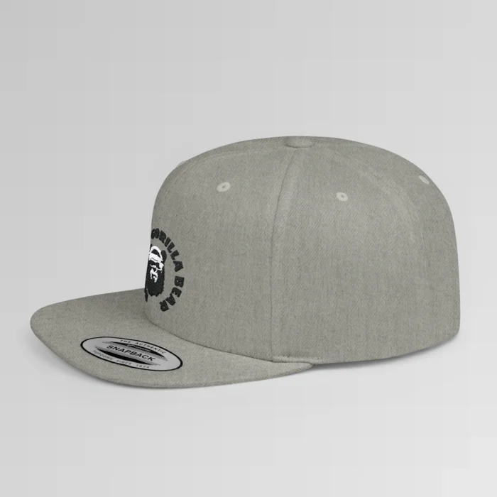 A mockup of a side view of the "BBGB Flat Bill Snapback Cap", with "Big Baby Gorilla Bear" embroidered in a circular font pattern surrounding the Big Baby Gorilla Bear Mascot embroidered on a heather grey cap.