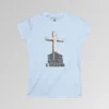 The front of a t-shirt with 3D text which states "The Rock On Which I Stand", from a slightly left perspective, in the shape of a simple house, with an old, wooden cross in the background. Color: Light Blue. Her Style.