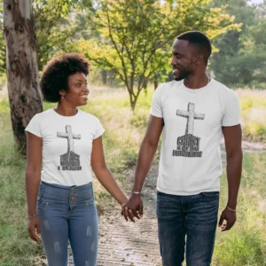 A couple walking hand in hand out in nature, wearing a white couple's shirt combination, with the "Christ Foundation" and "Rock on Which I Stand" tees from BigBabyGorillaBear.Com. These tees have different text, but share an old, wooden cross and similar styles.