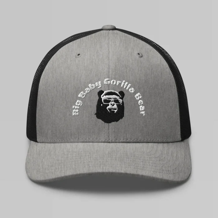 Front side view of a Heather Black mesh trucker cap, with the Big Baby Gorilla Bear mascot's face and the Big Baby Gorilla Bear Name Embroidered in black and white on the front of the cap.