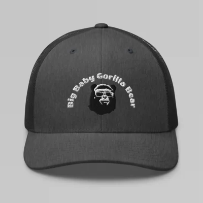 Front side view of a Heather Gray mesh trucker cap, with the Big Baby Gorilla Bear mascot's face and the Big Baby Gorilla Bear Name Embroidered in black and white on the front of the cap.