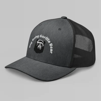 Left side view of a Heather Gray mesh trucker cap, with the Big Baby Gorilla Bear mascot's face and the Big Baby Gorilla Bear Name Embroidered in black and white on the front of the cap.
