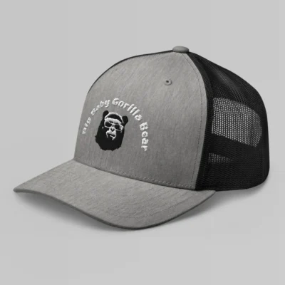 Left side view of a Heather Black mesh trucker cap, with the Big Baby Gorilla Bear mascot's face and the Big Baby Gorilla Bear Name Embroidered in black and white on the front of the cap.