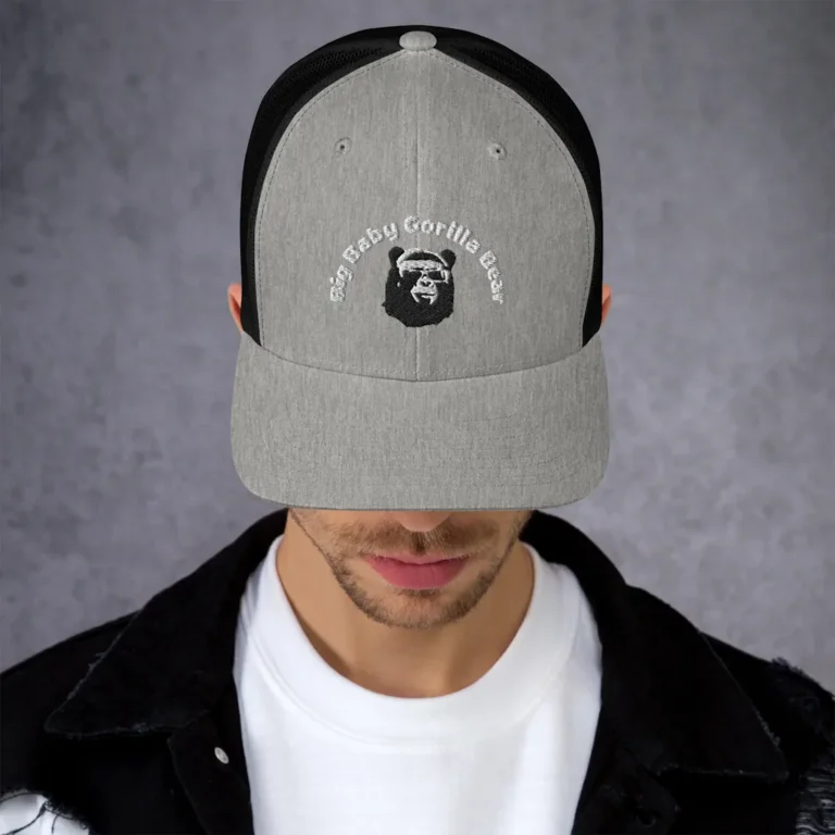 A male wearing a mockup of a two tone, trucker cap (light grey and black), with the Big Baby Gorilla Bear Mascot and Company name embroidered on the front.