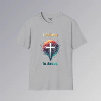 A sport grey colored t-shirt with the words "I Believe" and "In Jesus" above and below a Christian cross, with a gradient white to very light blue filling the cross.. Around the cross is a vibrant circle with lines like stars shooting out, in the colors ranging from yellow to orange, pink, to teal and blue. The words "I Believe" has a gradient fill color of yellow to orange. The words "In Jesus" has a gradient fill color of teal to dark teal/blue.