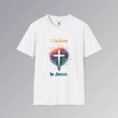 A white colored t-shirt with the words "I Believe" and "In Jesus" above and below a Christian cross, with a gradient white to very light blue filling the cross.. Around the cross is a vibrant circle with lines like stars shooting out, in the colors ranging from yellow to orange, pink, to teal and blue. The words "I Believe" has a gradient fill color of yellow to orange. The words "In Jesus" has a gradient fill color of teal to dark teal/blue.
