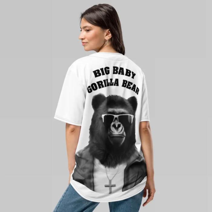 A female model, showcasing the backside of the BBGB Recycled Baseball Jersey from BigBabyGorillaBear.Com (White jersey). Has the words "Big Baby Gorilla Bear", stacked, and in curved font, with a super-imposed image of the Big Baby Gorilla Bear mascot, wearing sunglasses, leather jacket, and a Cross necklace.